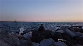 实拍视频男子独自一人坐在浪花拍打的礁石上看海
