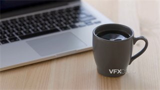 实拍视频将刚冲泡好的热咖啡放置桌面笔记本电脑旁