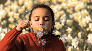 实拍视频卷发小女孩在种植鲜花的田野上吹出彩色泡泡
