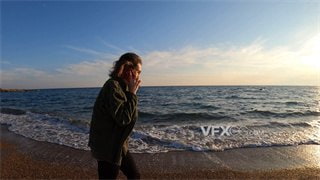 实拍视频女子在海边休闲漫步用手机与人交谈甚欢4K分辨率