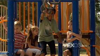 实拍视频小男孩在游乐场用吊环向一群伙伴展现臂力