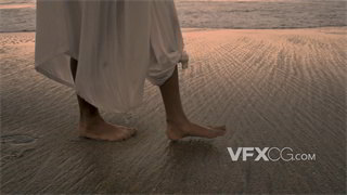 实拍视频身着白色长裙女子光脚悠闲在湿润松软沙滩上行走