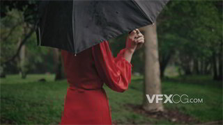 实拍视频一袭红裙女士优雅撑起黑色雨伞在雨中行走