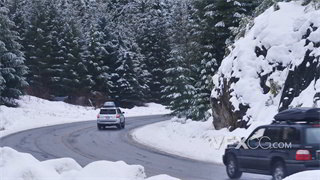 实拍视频汽车在白雪覆盖森林道路上转弯