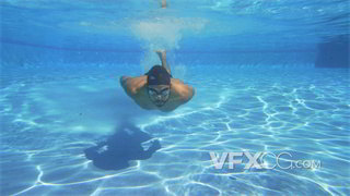 实拍视频身着游泳专用服装男子在水下游向游泳池里的摄像机