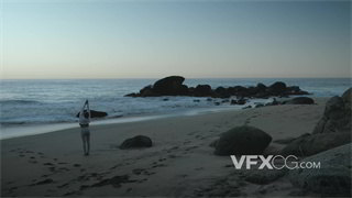 实拍视频远景拍摄日落涨潮时分在海边进行伸展